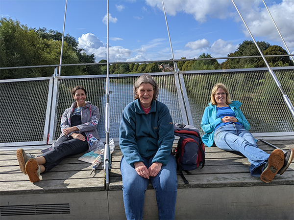 Three people enjoying a break on Millennium Bridge in York